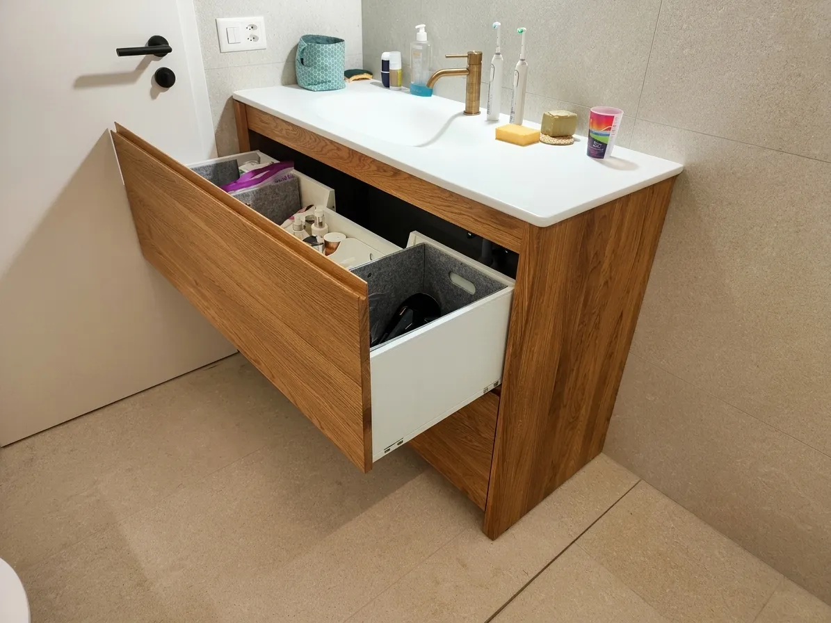 Detail of an open drawer in a walnut bathroom cabinet, showing the organised interior with grey felt dividers